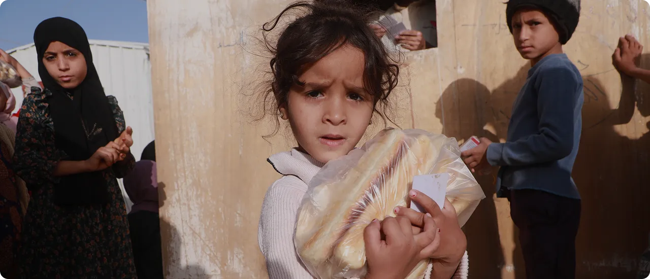 A child holding a fresh loaf of bread from a Freedom Bakeries distribution